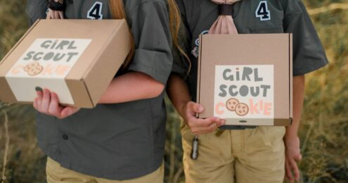 Two girls holding girls scout cookies boxes