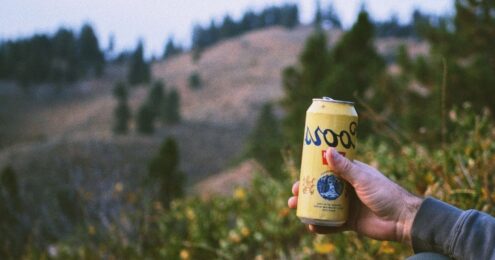 A hand holding a can of coors beer