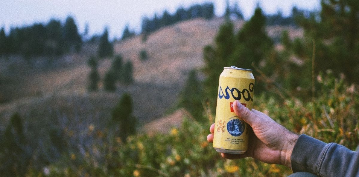 A hand holding a can of coors beer