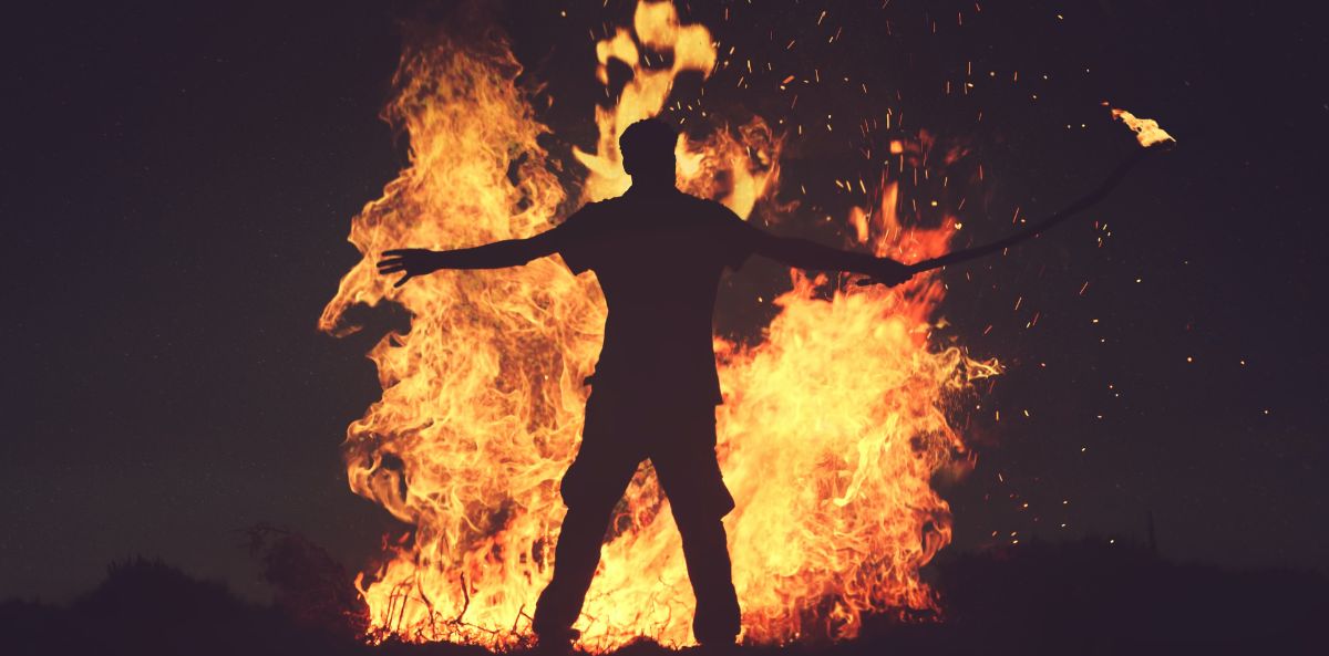 A mans silhouette standing in front of a fire