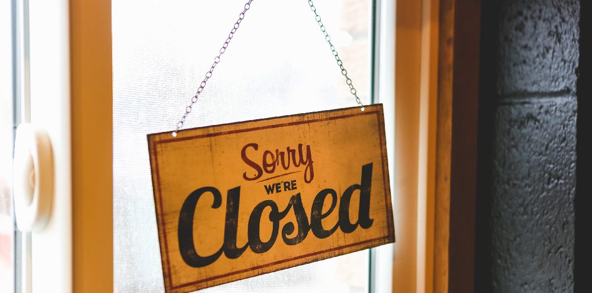 how to dissolve a nonprofit - a sorry we're closed sign hanging on a glass door